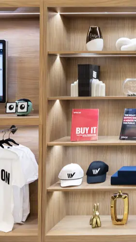 Custom wooden retail display unit with integrated shelf lighting showcasing branded apparel, books, and promotional merchandise, built by SoftSpace Exhibits for retail and experiential environments.