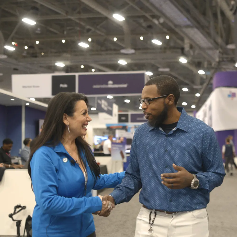 SoftSpace Exhibits team member greeting a client with a handshake on a trade show floor, demonstrating full-service event support and client management.